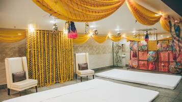 A room with two white beds, a chair, and yellow drapes.