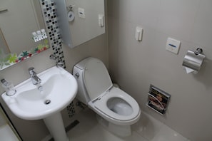 Casa de banho com lavatório branco, sanita e espelho com detalhes decorativos.