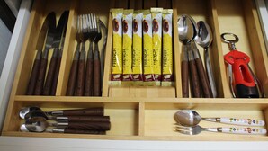 Un tiroir contenant divers ustensiles de cuisine, notamment des couteaux, des fourchettes, des cuillères et un ouvre-boîte.