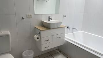 Ein modernes Badezimmer mit Toilette, Waschbecken, Waschtisch und Badewanne.