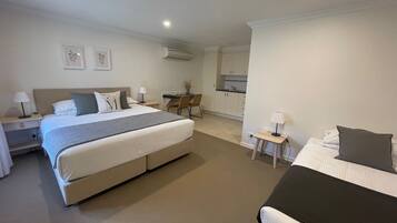 Una habitación de hotel con una cama grande, una cama más pequeña, un escritorio y una kitchenette.