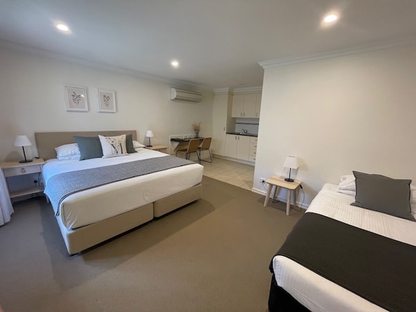 A hotel room with a large bed, a smaller bed, a desk, and a kitchenette. - Millthorpe Boutique Motel (Millthorpe)