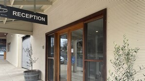 A reception area with a sign, a wooden door, and a potted plant.