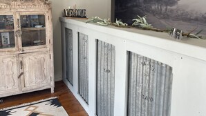 A reception area with a wooden cabinet, a welcome sign, a clock, and a landscape painting.