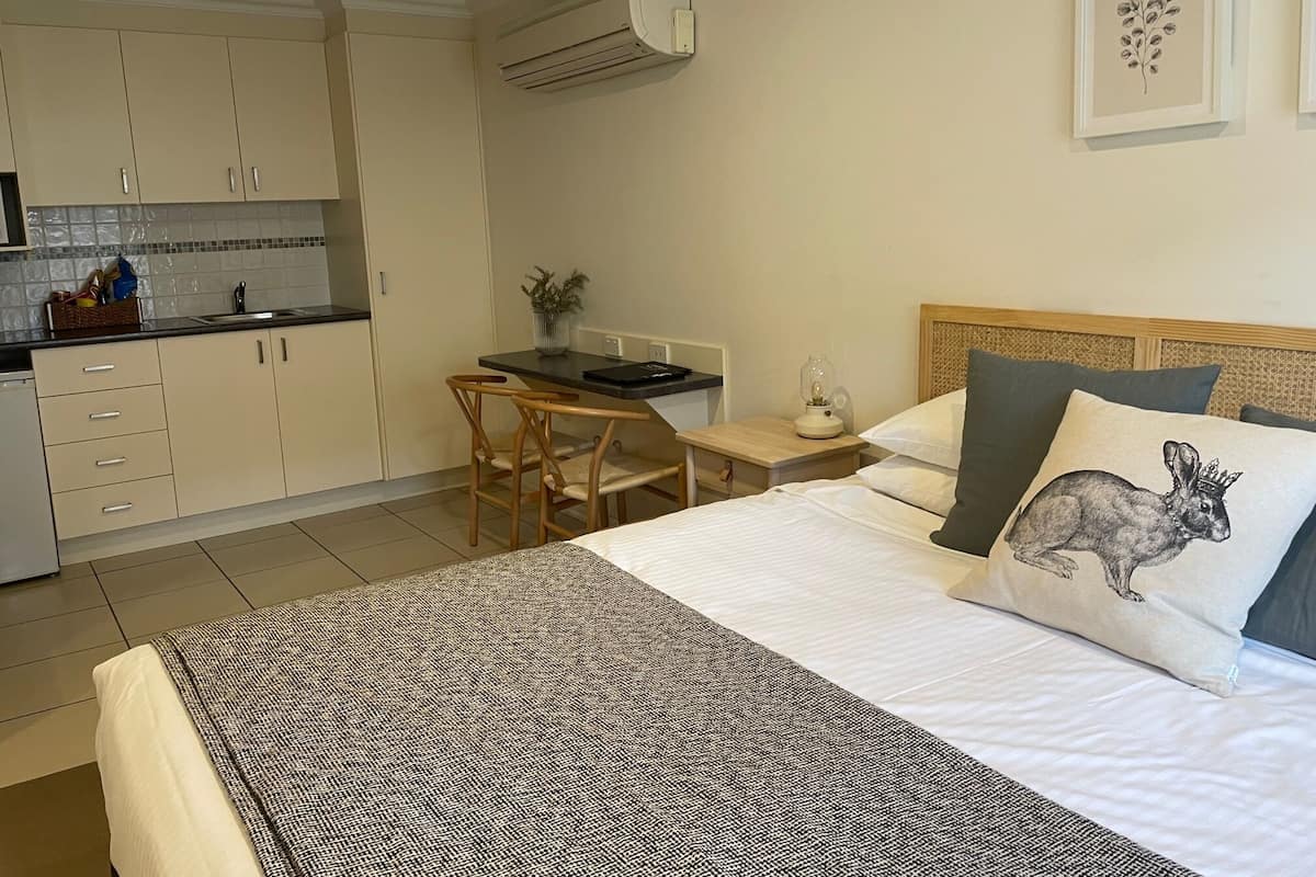A compact hotel room with a bed, a desk, and a kitchenette.