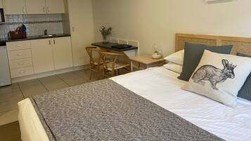 A compact hotel room with a bed, a desk, and a kitchenette.