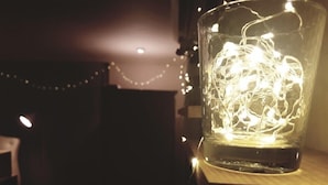 A glass container with a string of lights inside, placed on a wooden surface. - Gangnam Rodem (Seoul)