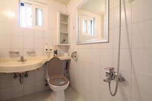 A bathroom with a toilet, sink, and shower.