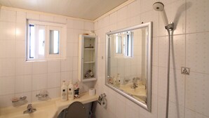 A bathroom with a large mirror, a shower, and a vanity with toiletries. - Gangnam Rodem (Seoul)