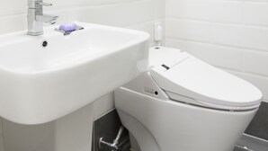 A modern bathroom with a white sink, a toilet, and a mirror above the sink. - Ivory Central Gangnam (Seoul)