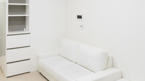 A white room with a white sofa, a white cabinet, and a ceiling light fixture. - Ivory Central Gangnam (Seoul)