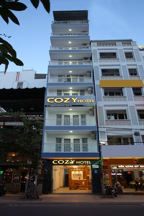 A multi-story building with a prominent "COZY HOTEL" sign on the ground floor.