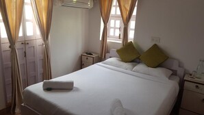 A neatly made bed with white linens, two pillows, and a folded towel. - Marquito's Guest House (Panaji)