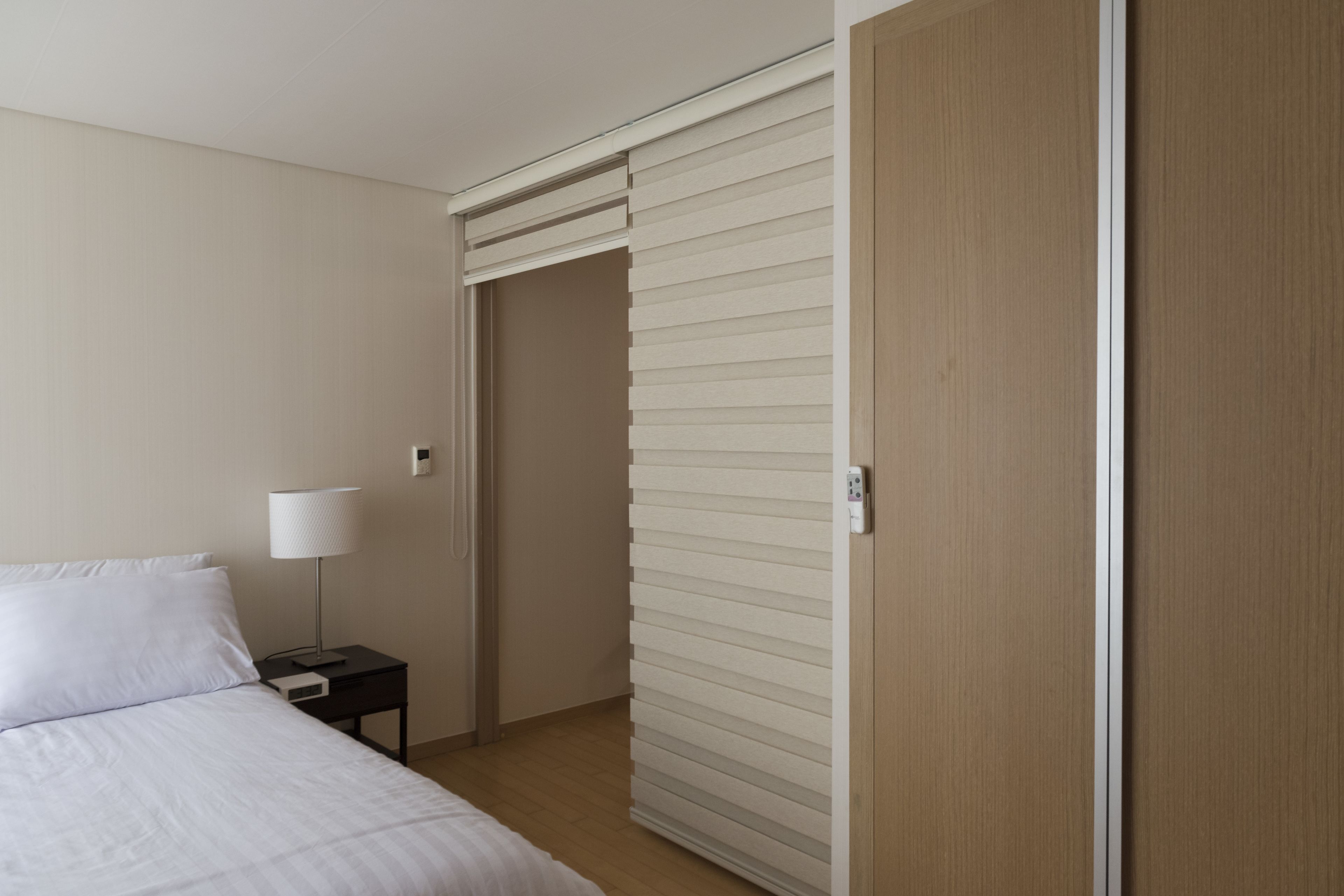 A hotel room with a bed, nightstand, lamp, and a sliding door.