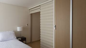 A hotel room with a bed, nightstand, lamp, and a sliding door.