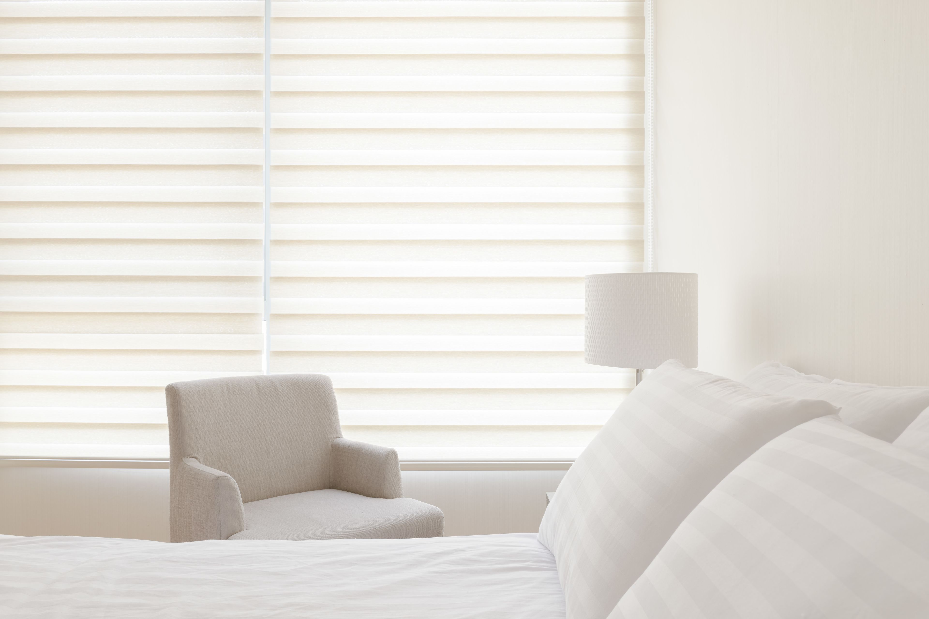 Una habitación de hotel con una cama, una silla y una lámpara.