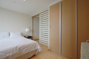 A bedroom with a bed, a nightstand, a lamp, and a sliding door closet. - Galleria Palace 2 (Seoul)