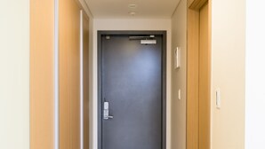 A hallway with a wooden floor, a grey door at the end, and a white mat in the center. - Galleria Palace 2 (Seoul)