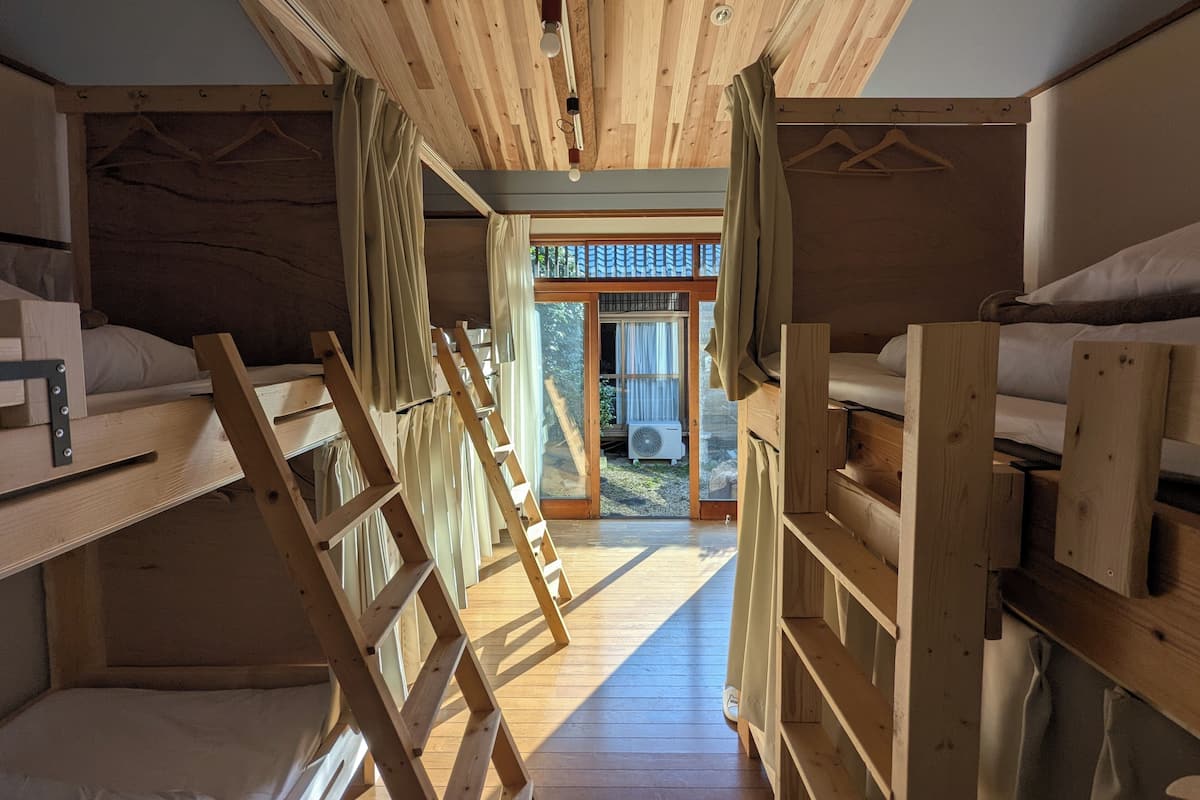 A compact, wooden cabin with bunk beds, a ladder, and a sliding door leading to an outdoor area.