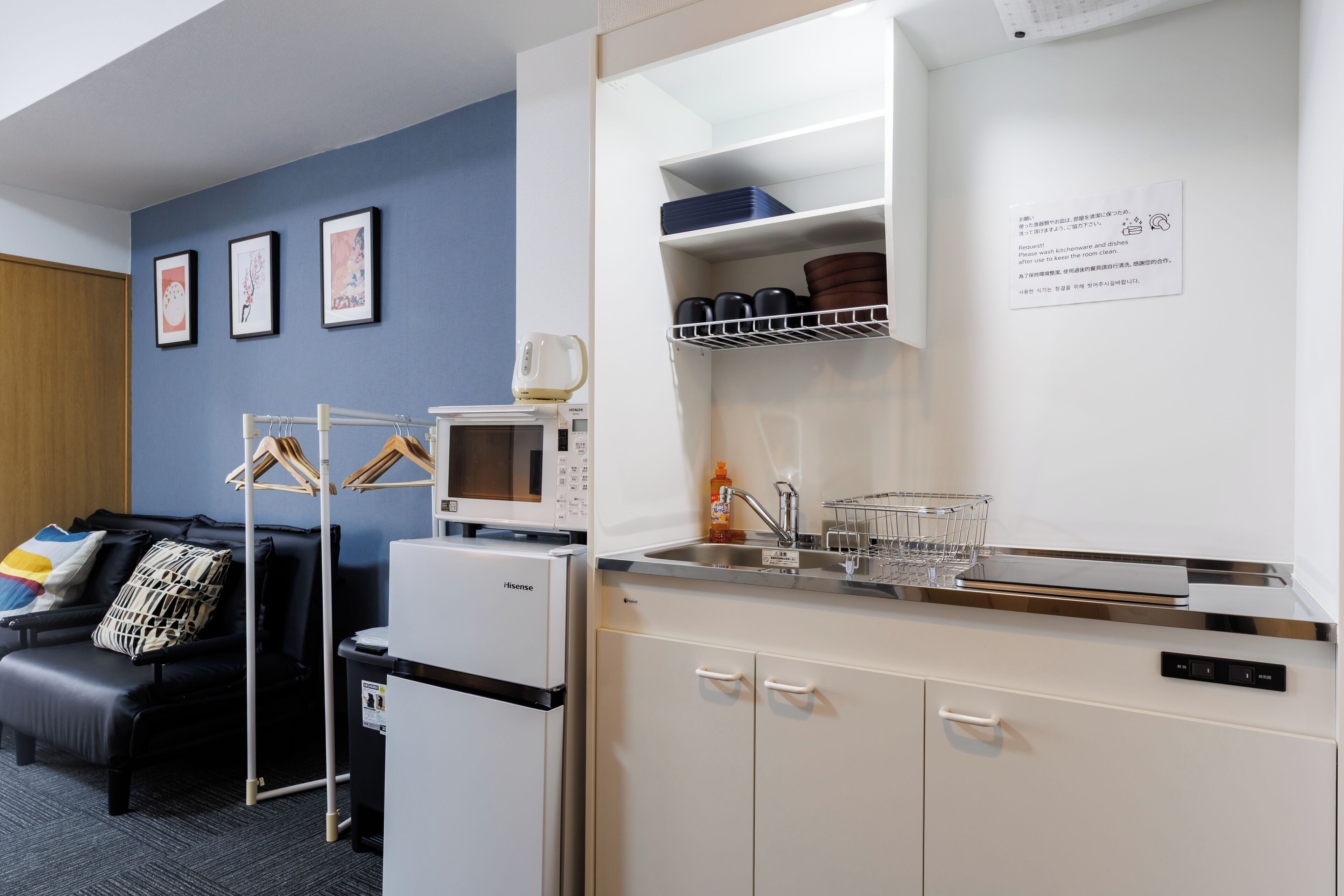 Une petite cuisine équipée d’un four à micro-ondes, d’un réfrigérateur et d’un évier. Un petit coin salon avec un canapé et un coussin est également à disposition.