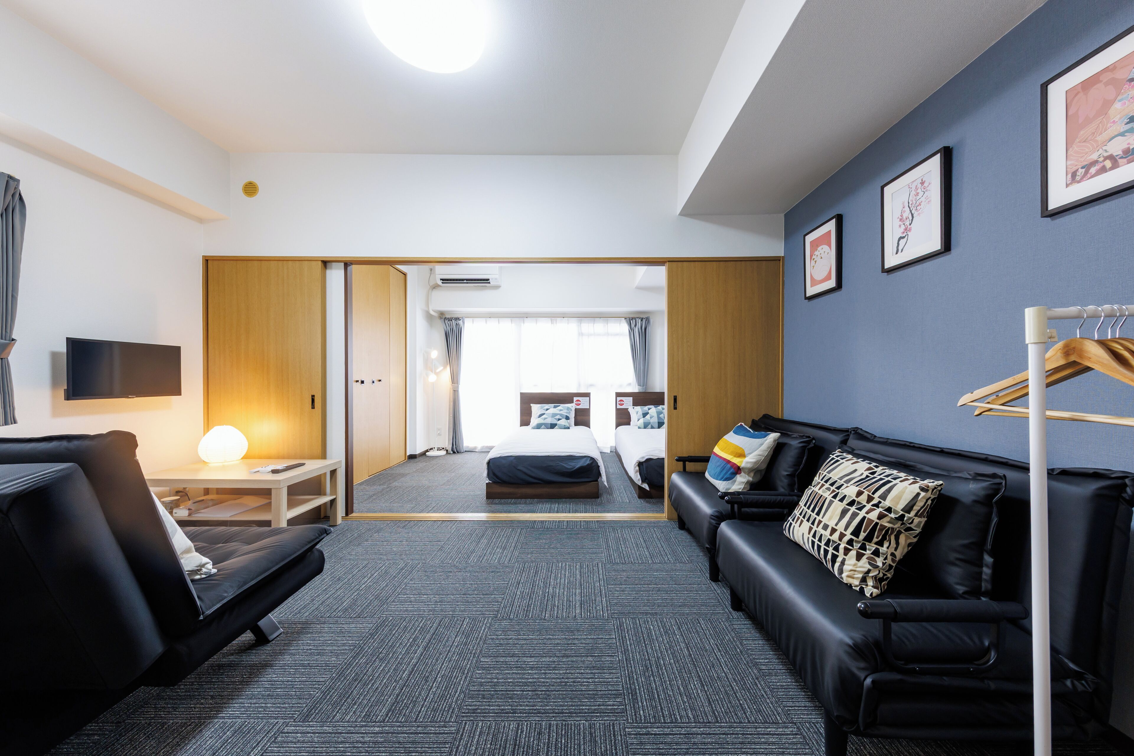 A modern hotel room with a sofa, a bed, a desk, and a TV.