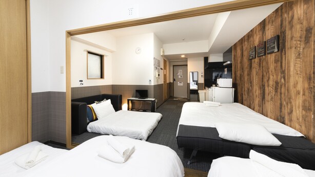 Una habitación de hotel con tres camas, una pared decorativa de madera, un reloj y un televisor.