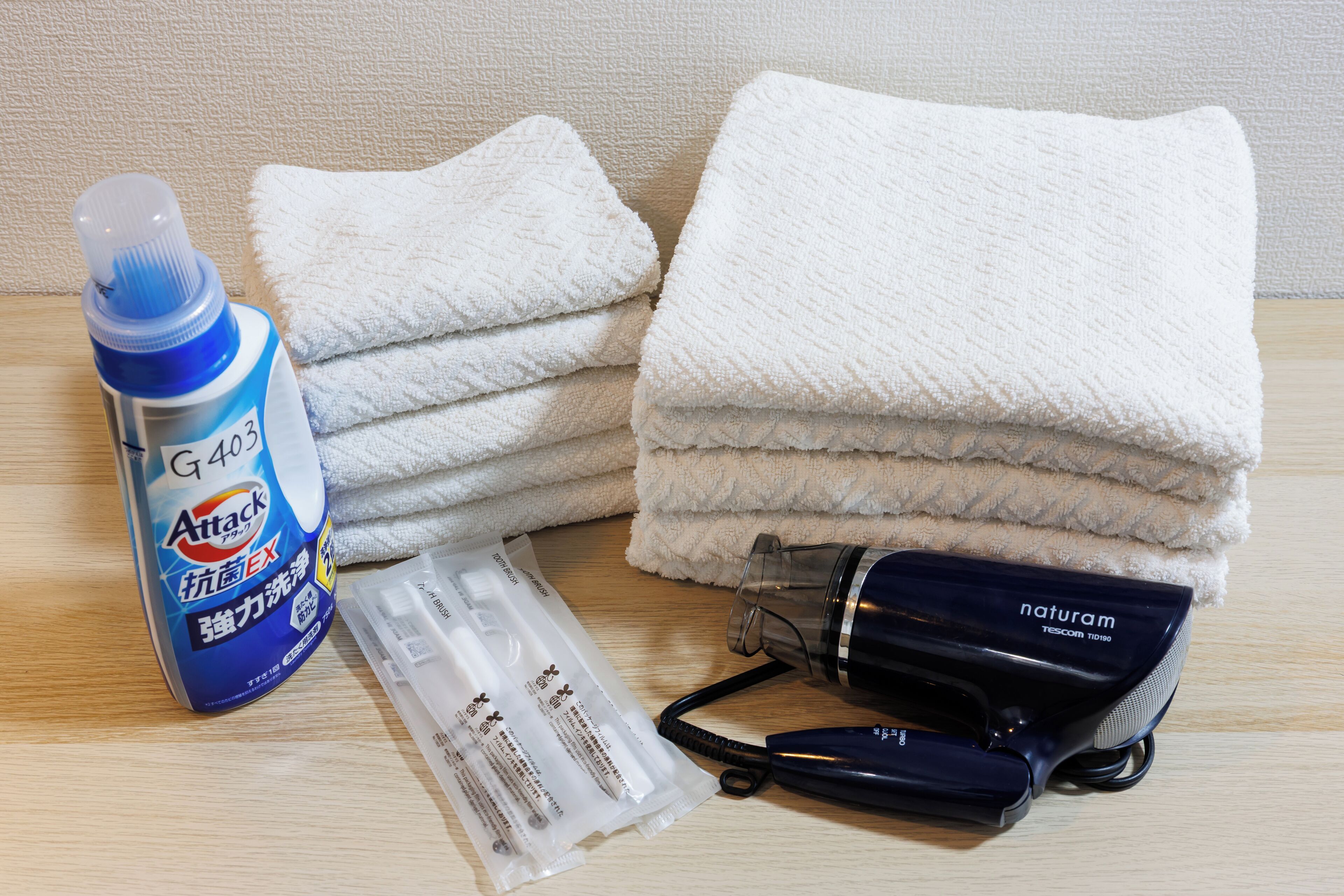 A bathroom with a towel stack, a bottle of hand soap, a hairdryer, and a pair of scissors.