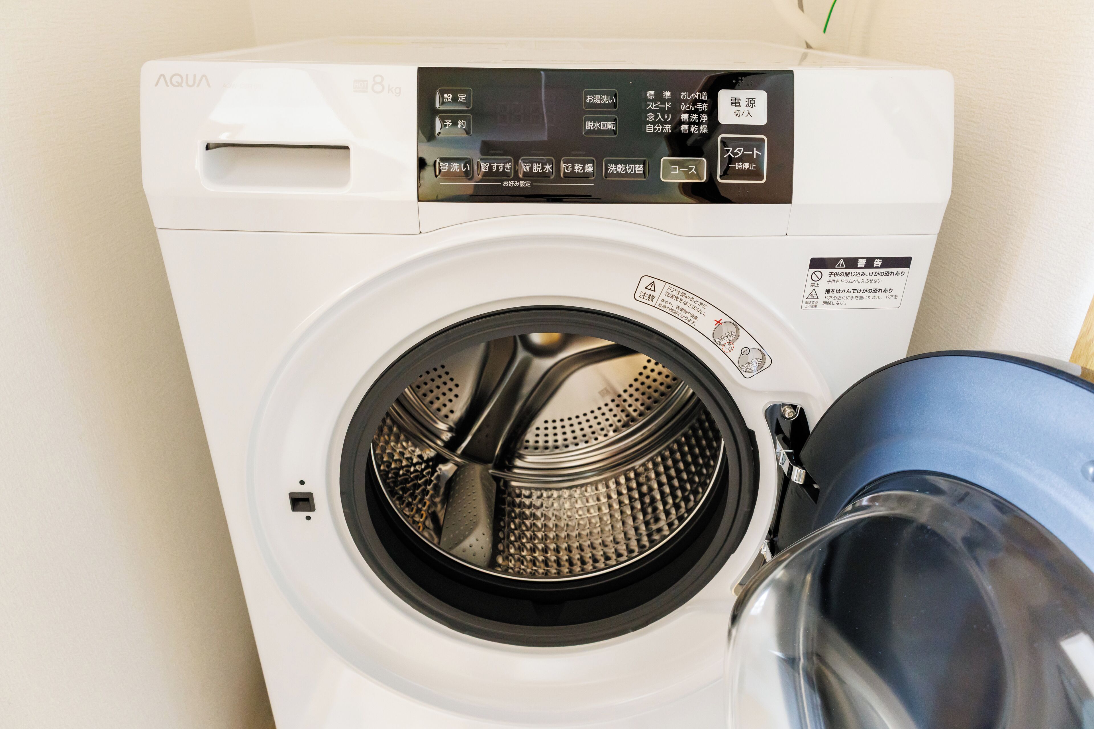 Une machine à laver à chargement frontal, dotée d’un panneau de commande et d’une porte transparente.
