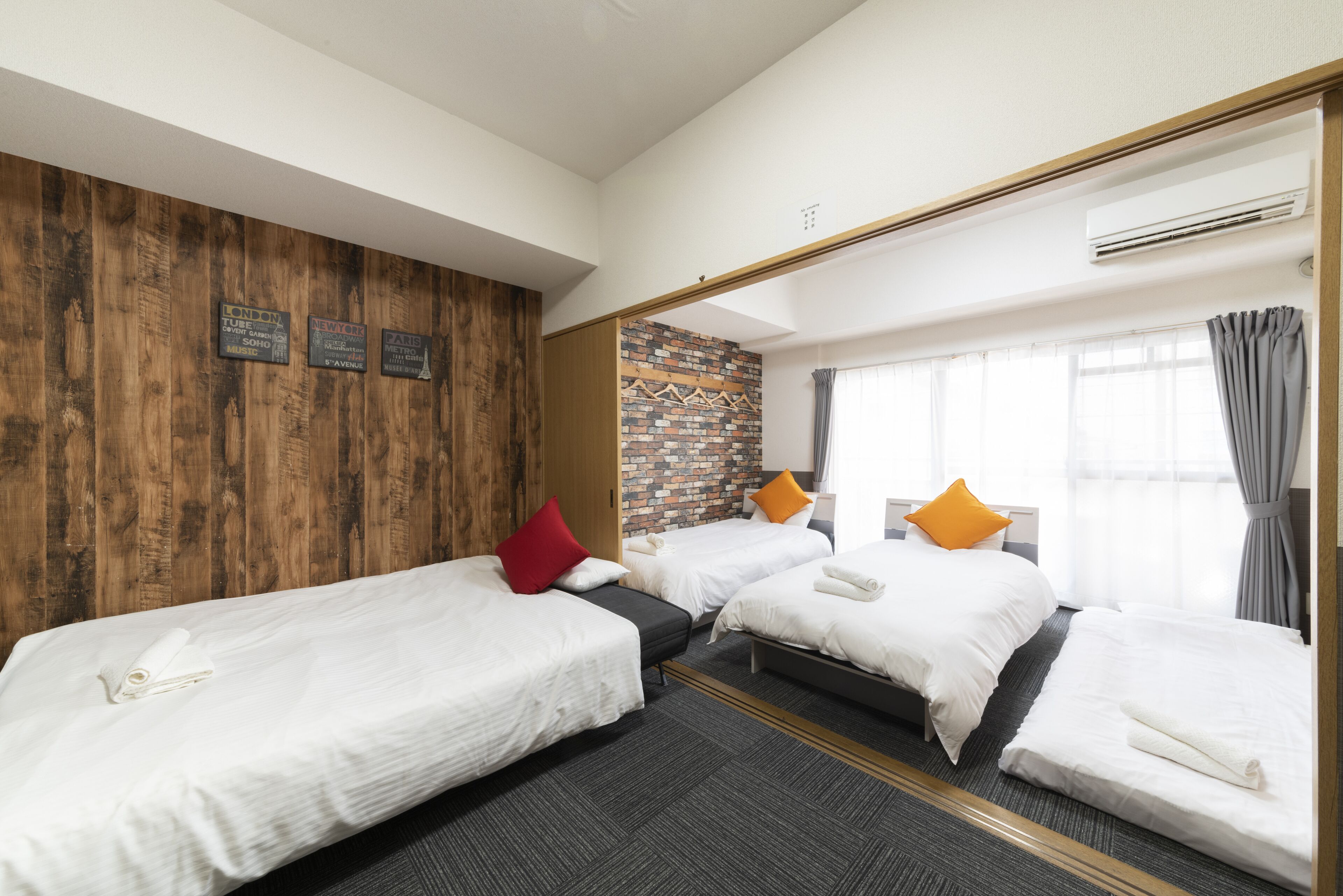 A hotel room with two beds, a brick accent wall, and a large mirror.