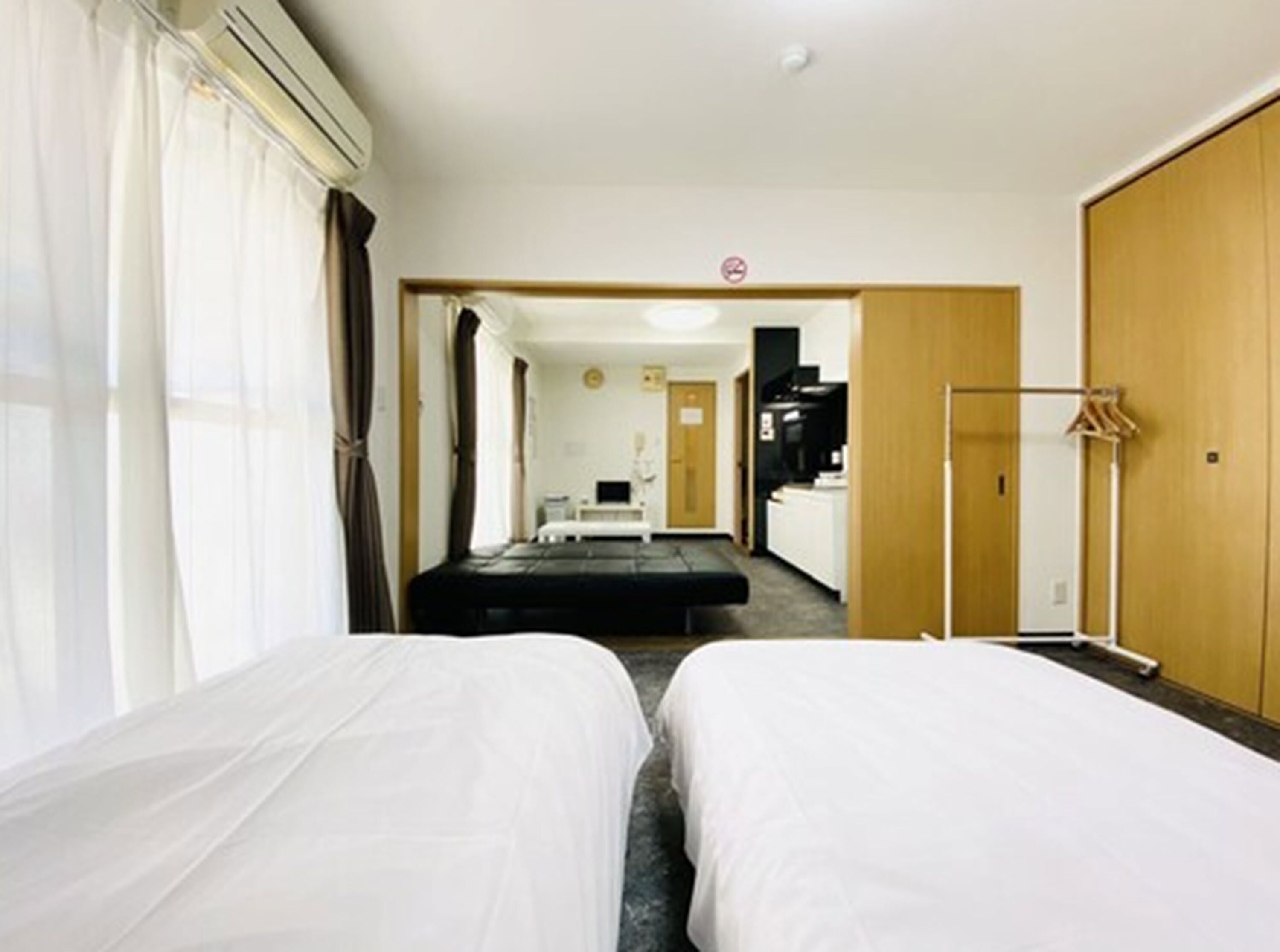 Una camera d'albergo con due letti, angolo cottura e bagno.