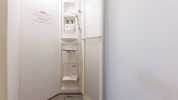 A bathroom with a toilet, a shower, and a sink. There is a caution sign on the wall.