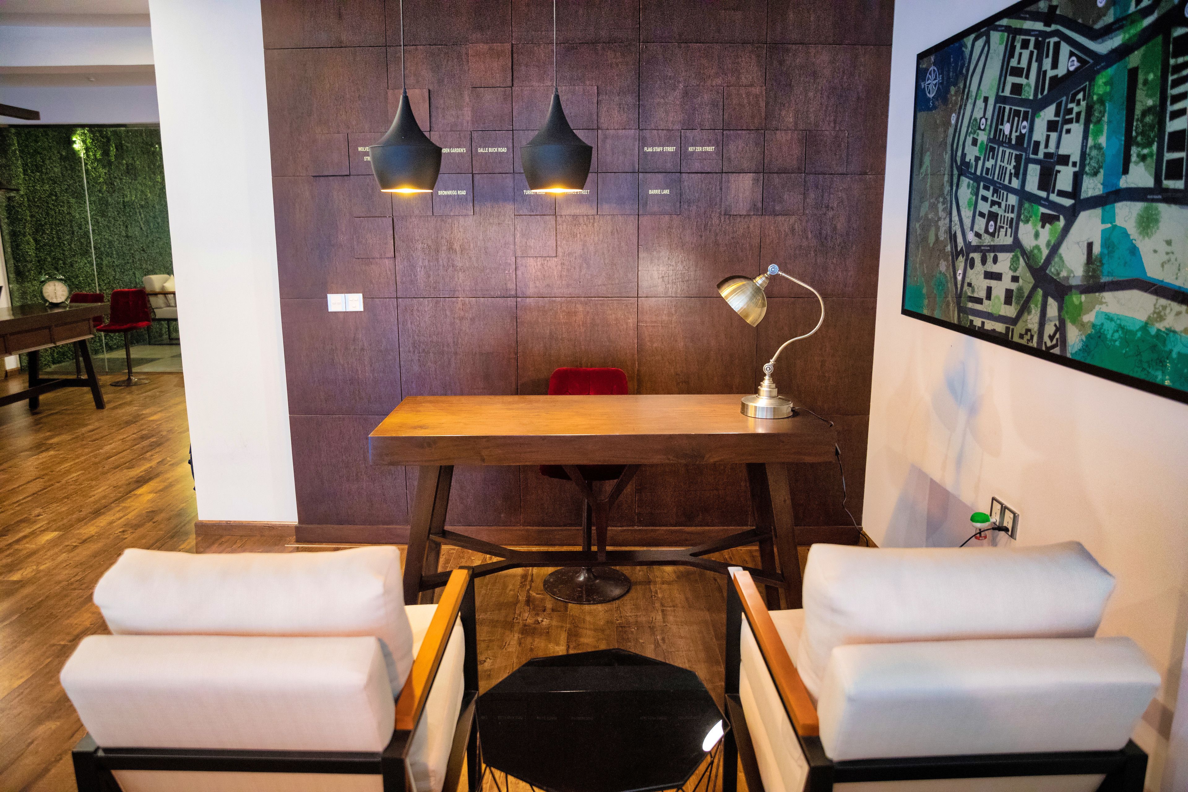 Un comedor moderno con una mesa de madera, dos sillas blancas acolchadas e iluminación colgante.