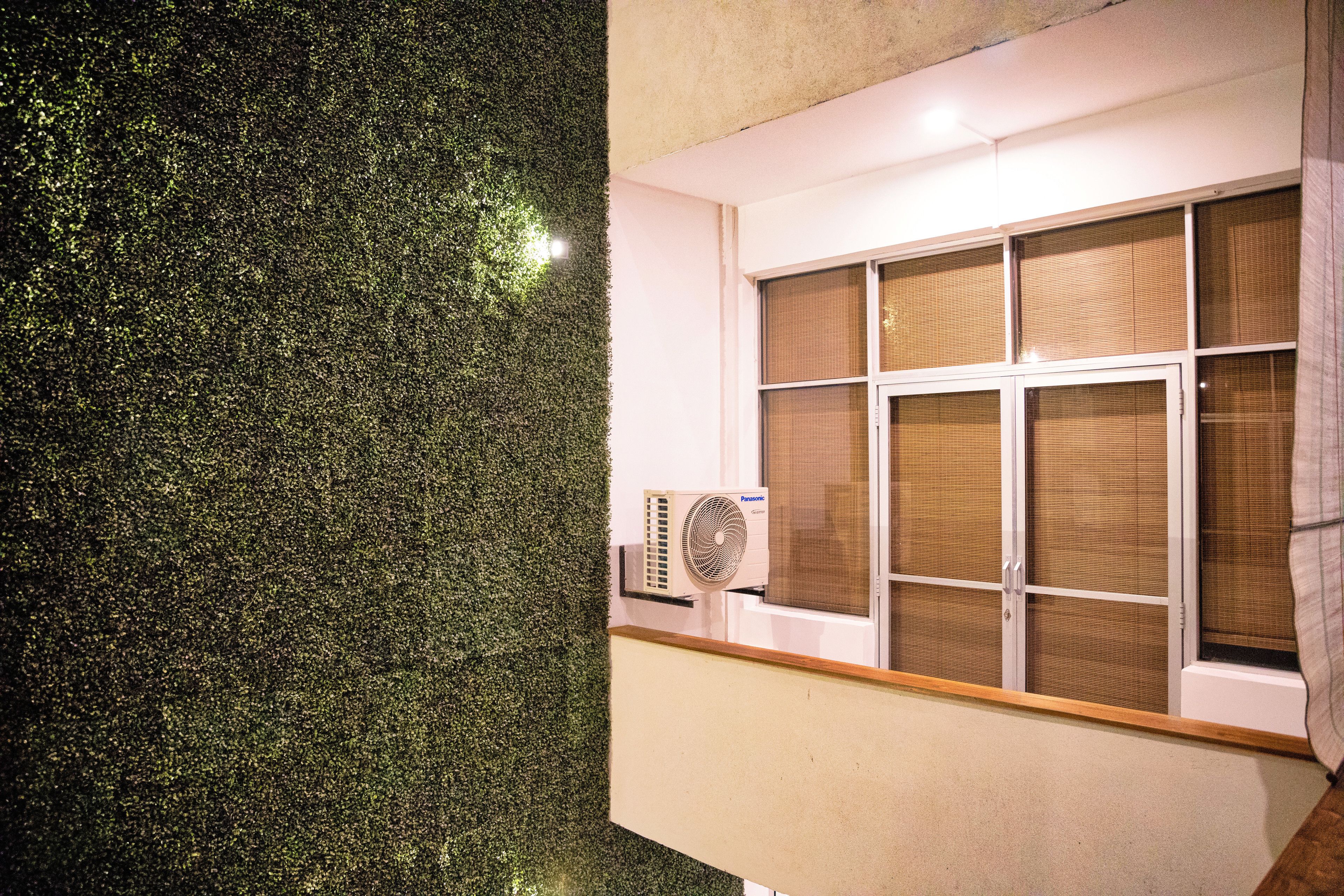 A room with a large window, a wall-mounted air conditioner, and a textured wall.