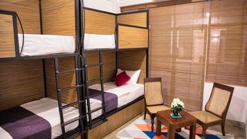 Ein Zimmer mit Etagenbetten, einem kleinen Tisch mit einer Vase und einem Stuhl.