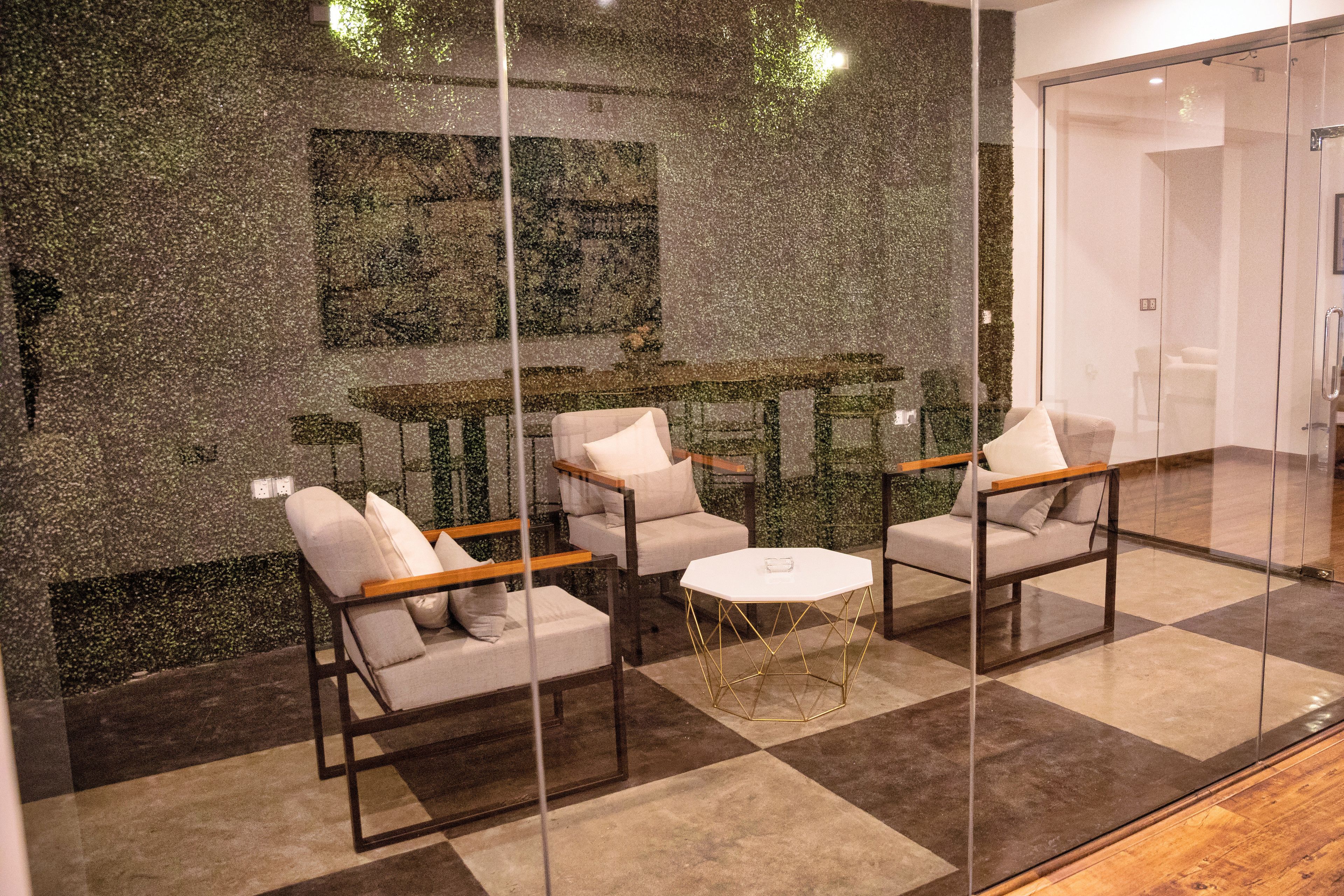 A modern interior with a checkered floor, glass partitions, and a seating area with white chairs and a round table.