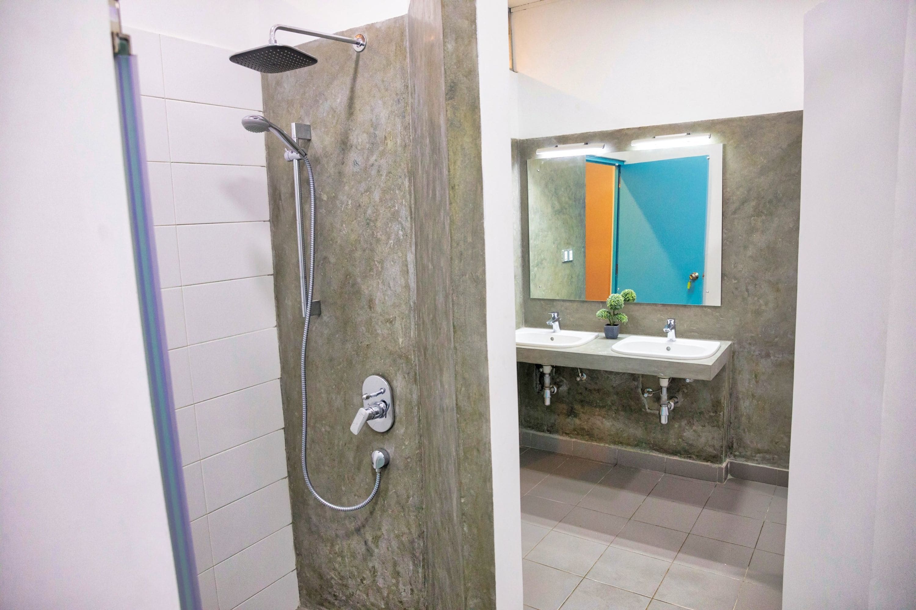 A bathroom with a shower, two sinks, and a mirror with a colorful reflection.