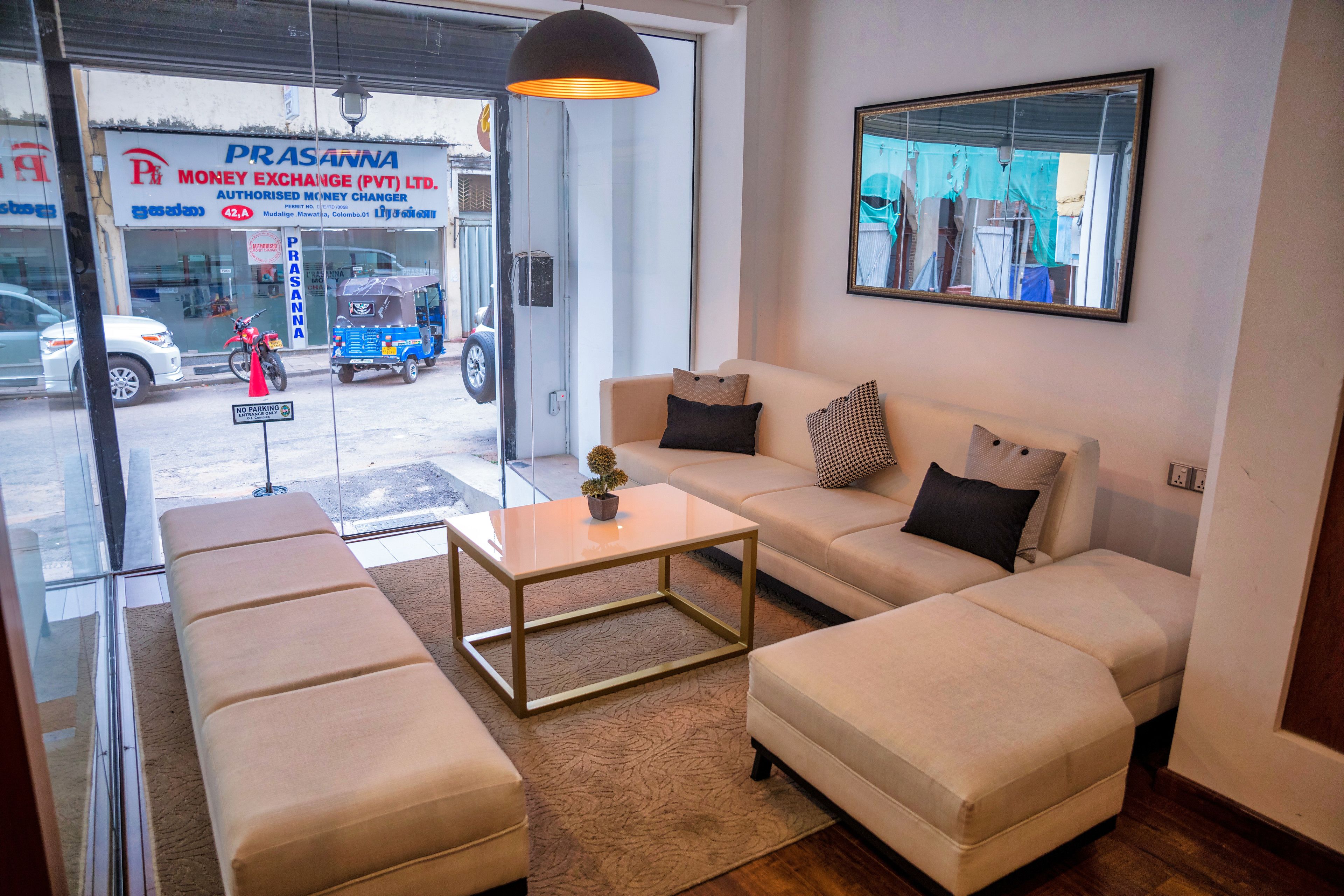 A modern interior with a sofa set, a coffee table, and a large window overlooking a street.