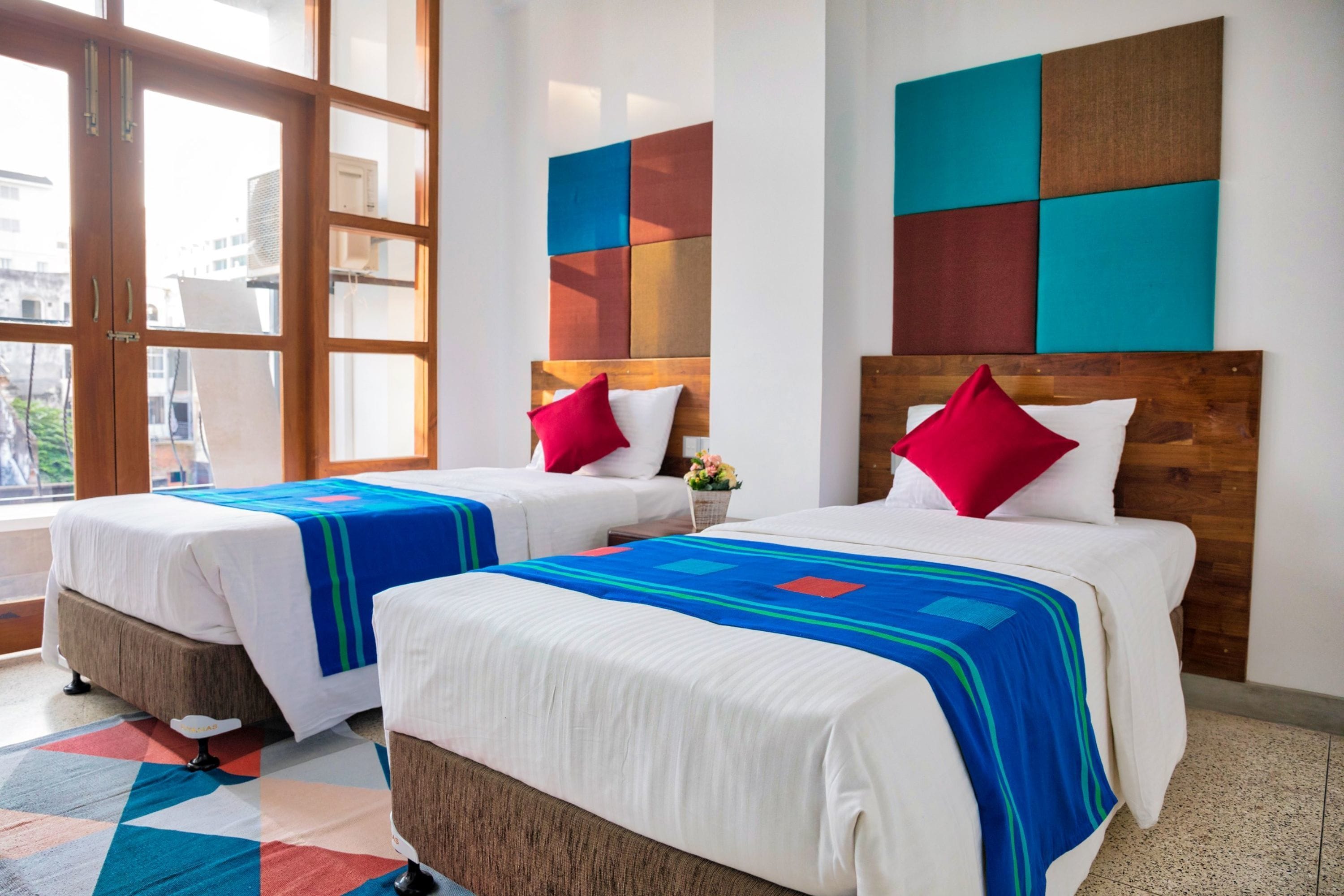 Two double beds with wooden headboards, white bedding, and colorful throw blankets.