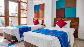 Two double beds with wooden headboards, white bedding, and colorful throw blankets.