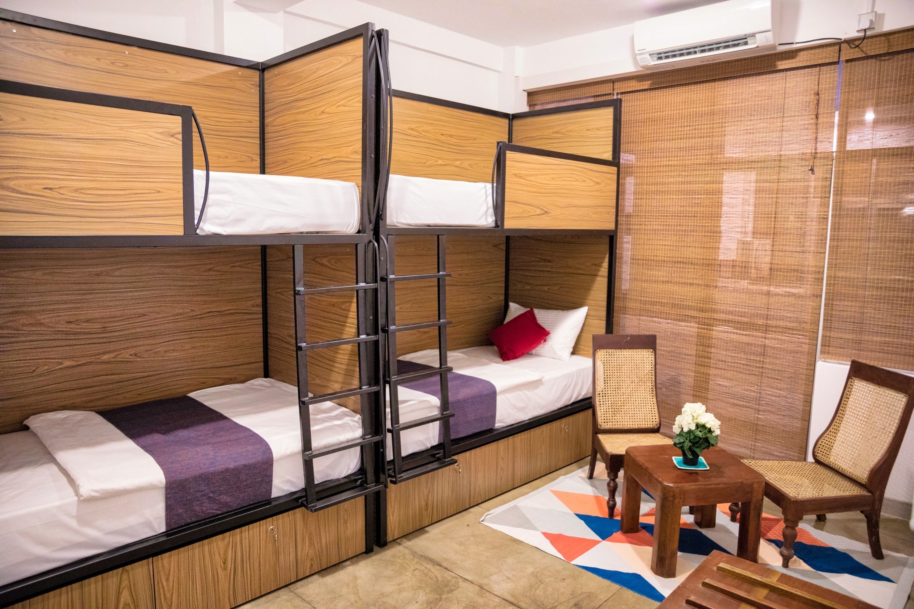 A room with bunk beds, a small table with a vase, and a chair.