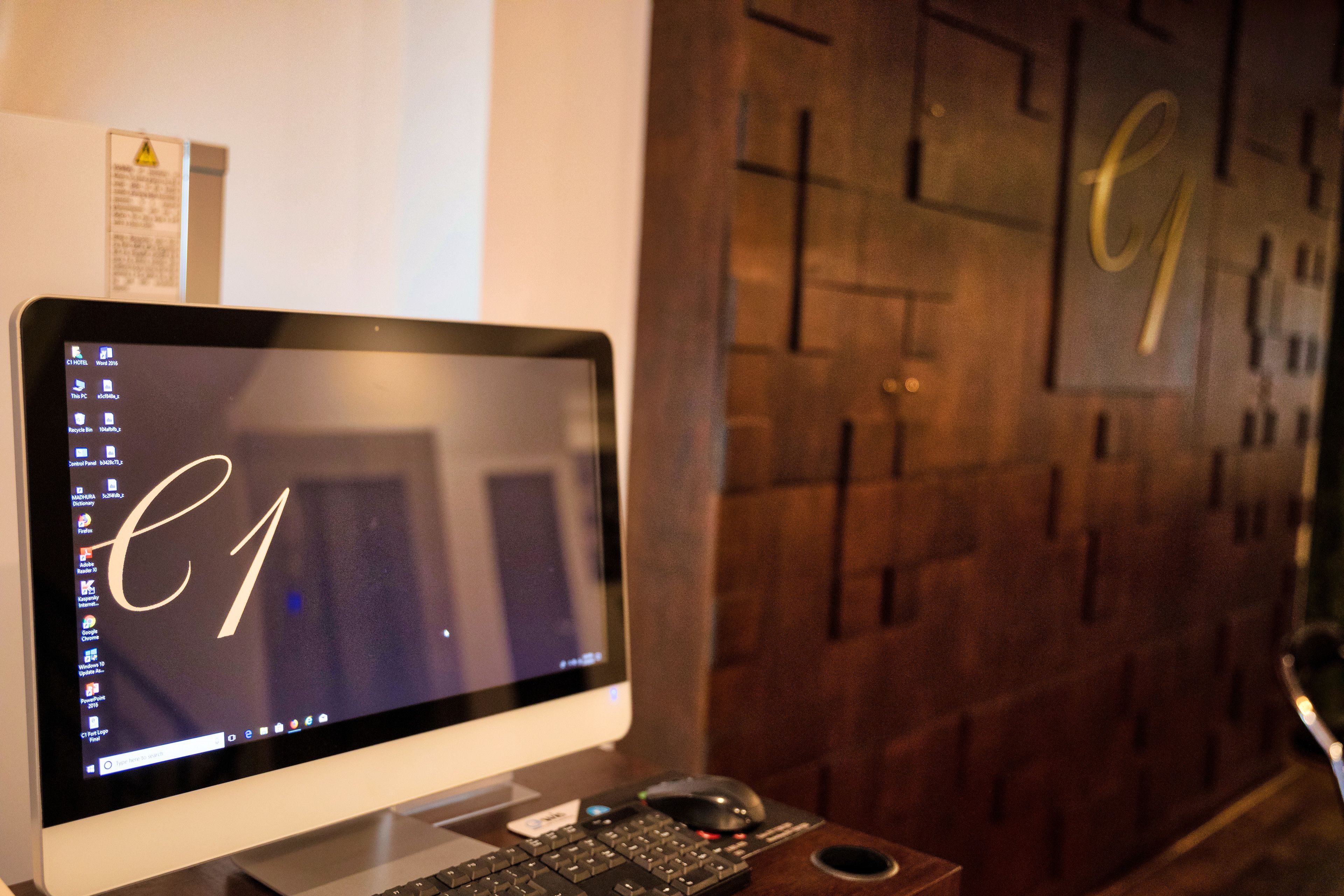 A desktop computer with a monitor displaying the Windows taskbar, a keyboard, and a mouse on a wooden desk.