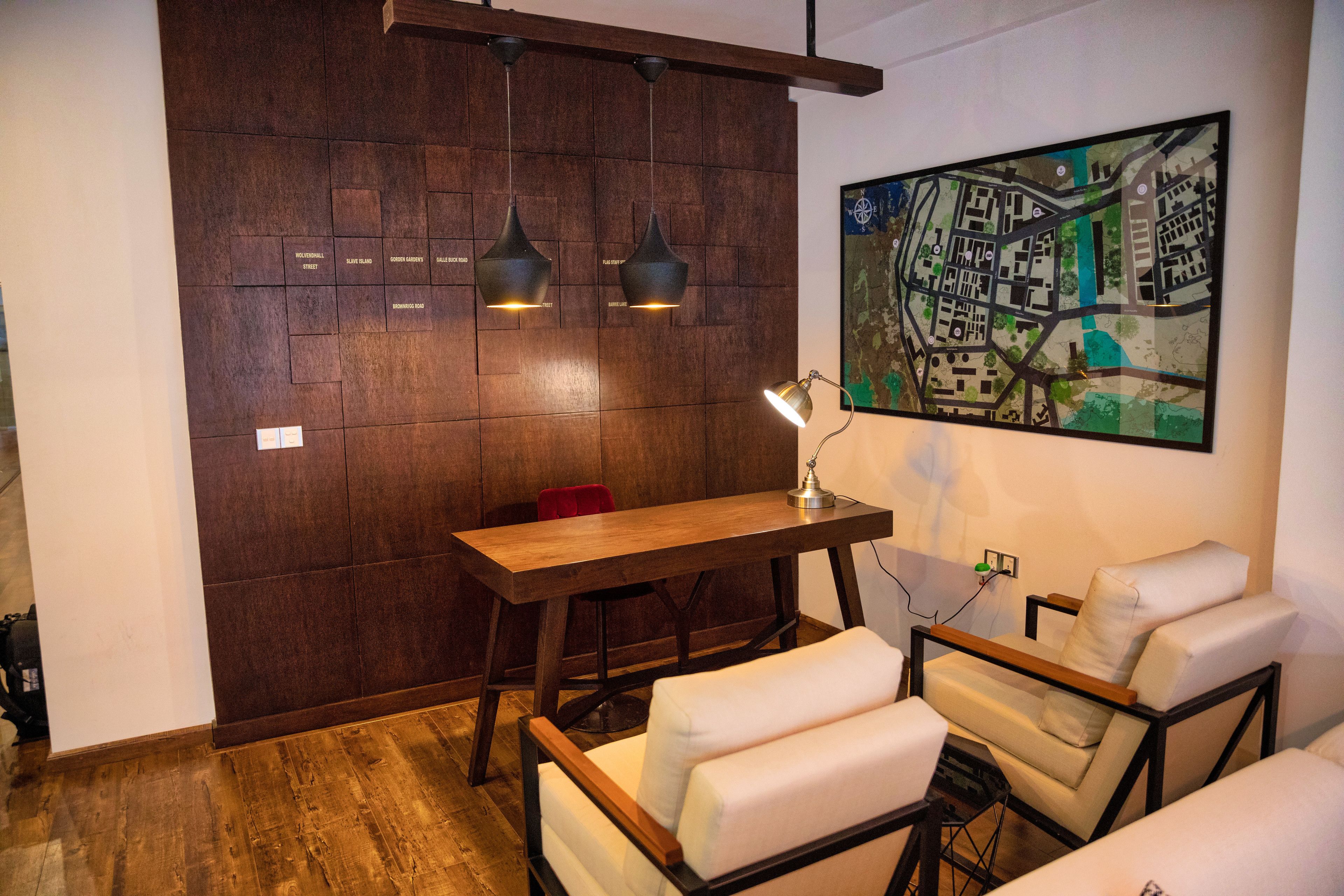 Un interior moderno con una pared de madera, una obra de arte con un mapa, una mesa de madera y dos sillas blancas acolchadas.