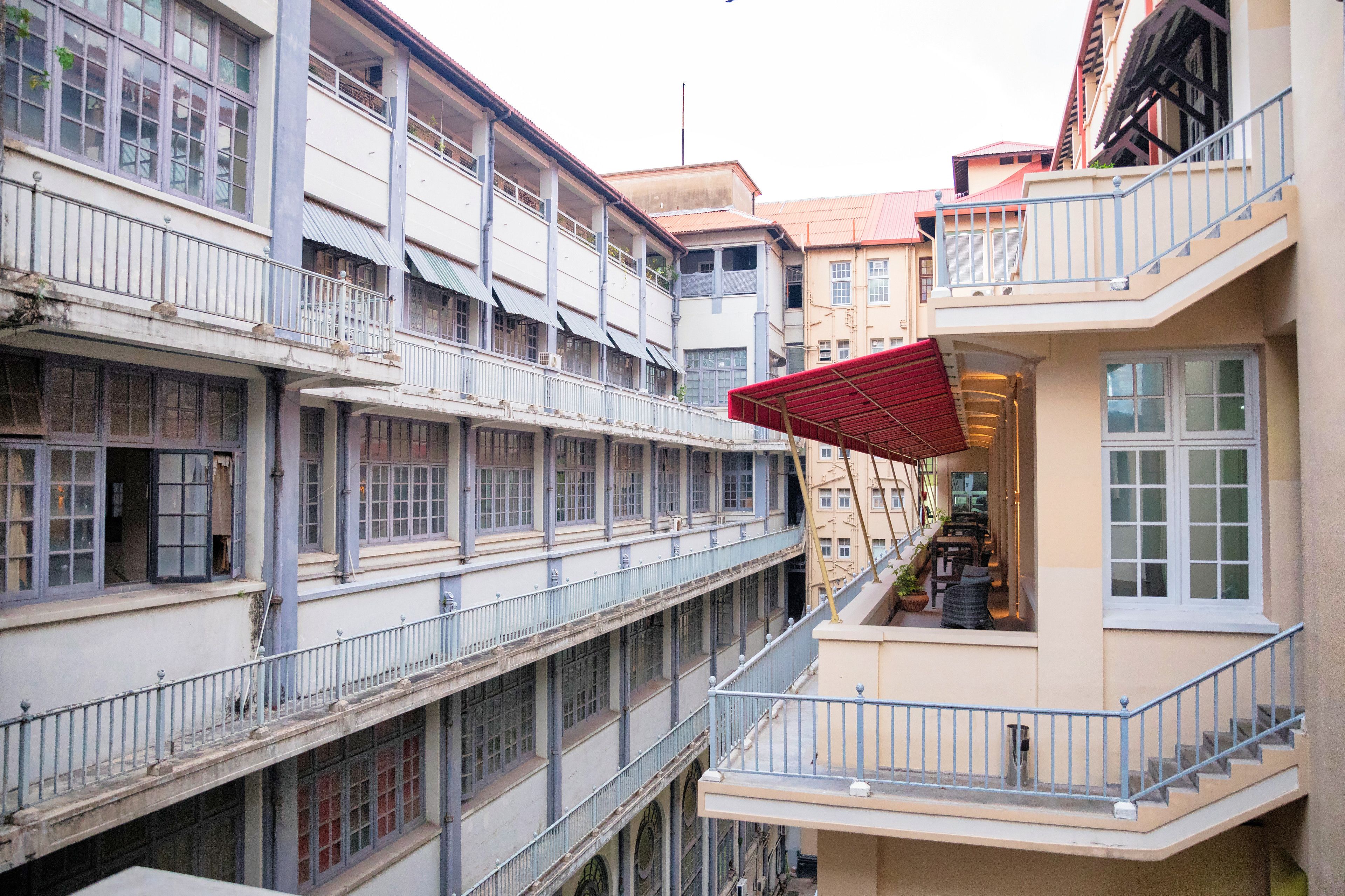 A multi-story building with balconies, a red awning, and a staircase.