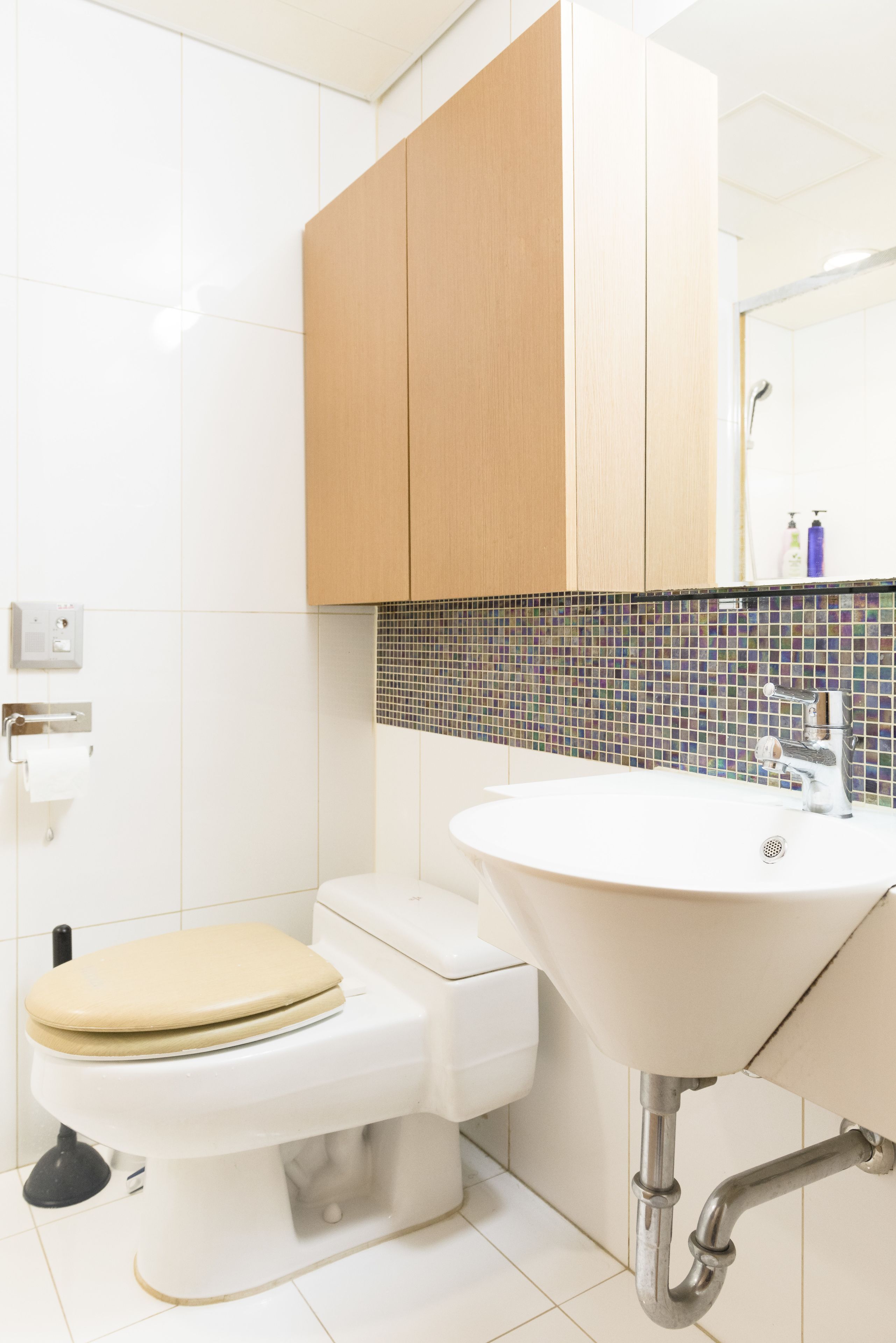 A modern bathroom with a toilet, sink, and wooden cabinets.
