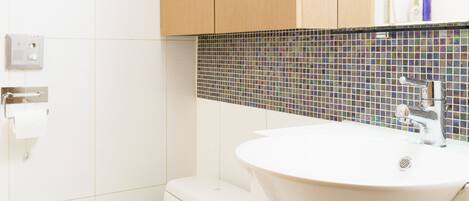 A modern bathroom with a toilet, sink, and wooden cabinets.