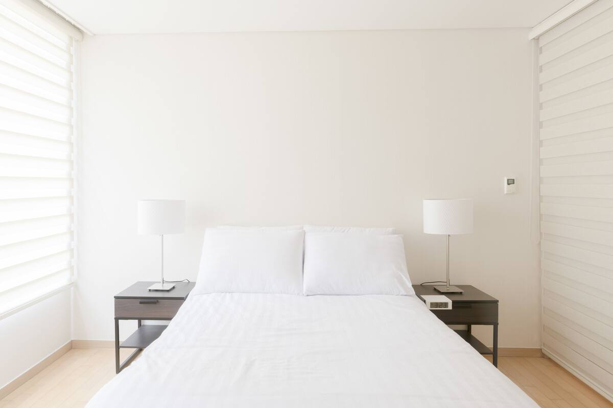 A minimalist bedroom with a single bed, two bedside tables, and a nightstand.