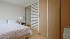 A bedroom with a bed, a nightstand, a lamp, and a sliding door closet. - Galleria Palace 3 (Seoul)