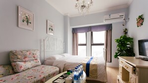 A hotel room with a bed, a sofa, a bedside table with a tray of toiletries, a television, and a window with curtains. - Chengdu Tu Le Apartment (Chengdu)