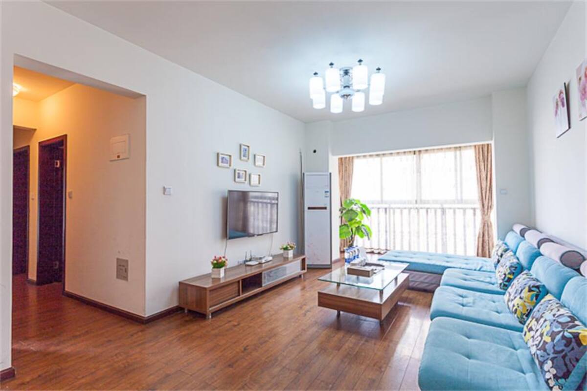 Una sala de estar moderna con un sofá, un televisor, una mesa de centro y una planta.