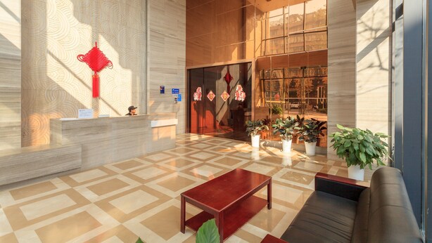 A modern lobby with a reception desk, seating area, and a large window with a view of the city. - Chengdu Tu Le Apartment (Chengdu)